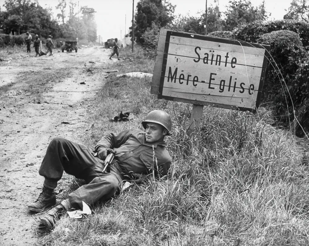 Lepäämässä oleva yhdysvaltalainen laskuvarjohyppääjä Sainte-Mère-Église'n lähellä | Taidetuloste historiallisesta valokuvasta